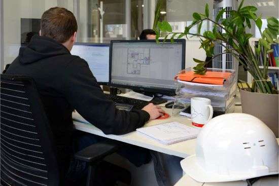 Expert Auris en Assistance à Maîtrise d'Ouvrage (AMO) analysant un projet immobilier sur ordinateur.