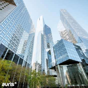 Vue sur des gratte-ciels modernes en verre, représentant le dynamisme du secteur immobilier et l’accompagnement des investisseurs par Auris en AMO et MOEx.